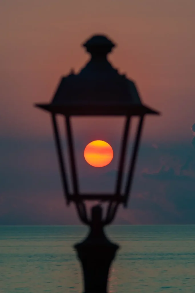 Lampadaire devant le soleil couchant, au bord de la mer
