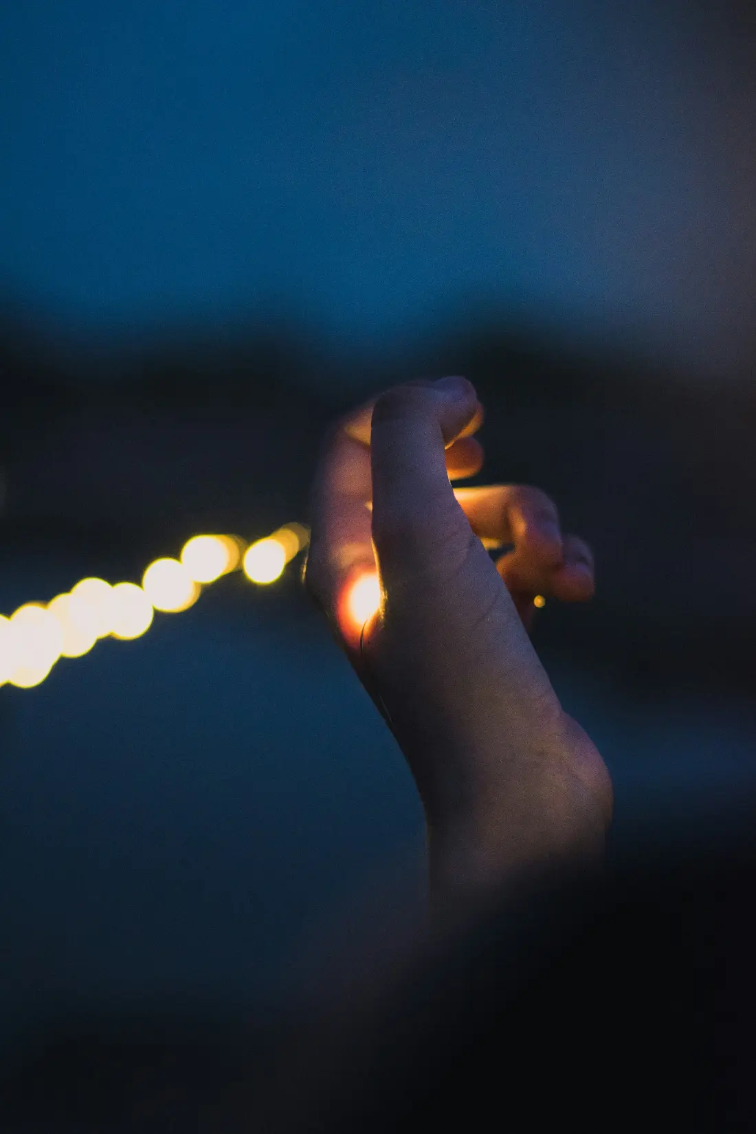 Main tenant une guirlande lumineuse dans la nuit